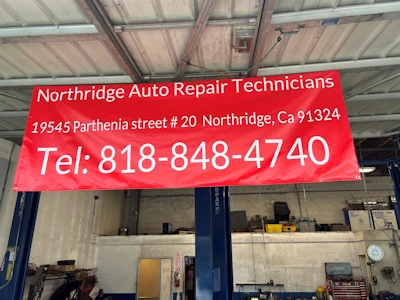 Northridge Auto Repair Technicians banner with address and phone number inside the repair bay